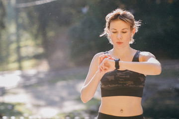 Fitness Woman In Wireless Earphones Using Smartwatch - obrazy, fototapety, plakaty