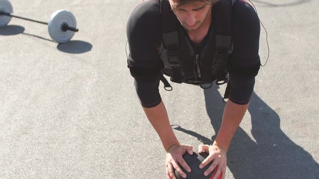 Awesome sportsman is doing exercises with a ball.