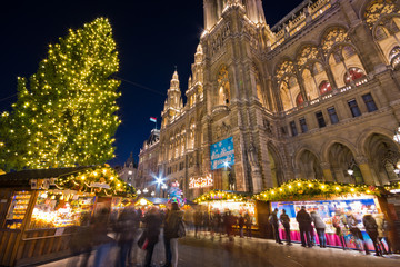 Famous Vienna Christkindlmarkt christmas market in front of town hall with huge Christmas tree at Rathausplatz with tourists and people in festive mood in Advent.