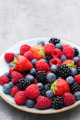 Fresh berry salad on blue dishes. Vintage wooden background.