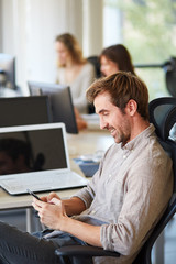 Man texting on his mobile phone while sitting in office
