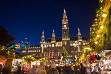 Famous Vienna Christkindlmarkt christmas fair in front of the town hall at Rathausplatz with tourists and people in festive mood on Advent evening. - obrazy, fototapety, plakaty