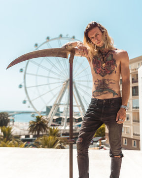 Tattooed man with scythe outdoors