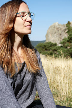 Woman meditating and doing yoga on the top of a mountain in nature