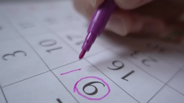 A man makes a date stamp in the calendar. Planning a vacation. Birthday. Close up. Marketing the date on the calendar, closeup.