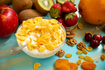 Tasty cornflakes with milk and fruits in glass bowl