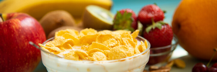 Tasty cornflakes with milk and fruits  in glass bowl