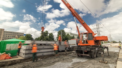 Unloading concrete plates from truck by crane at road construction site timelapse.
