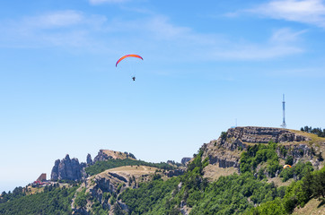 Fototapeta na wymiar Paraglider soaring above the mountain top. Russia, Republic of Crimea. 06.13.2018. Paraglider flight over Ai-Petri mountain