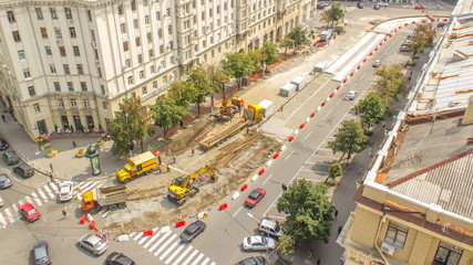 Orange construction telescopic mobile crane loading old tram rails into truck timelapse.