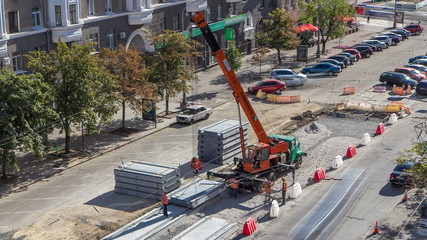 Installing concrete plates by crane at road construction site timelapse.