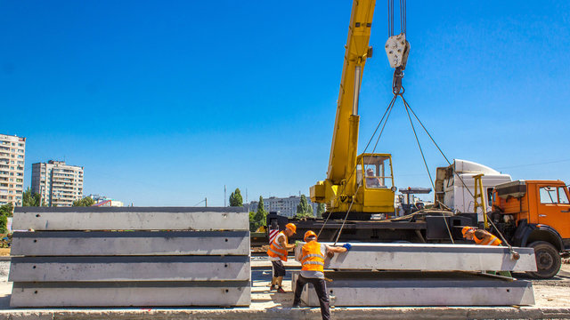 Installing concrete plates by crane at road construction site timelapse.