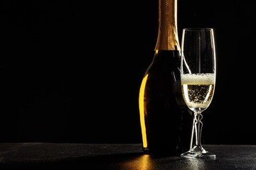 bottle of champagne and glasses over dark background