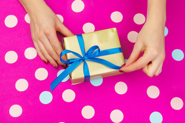 Woman hands holding gift box on pink background