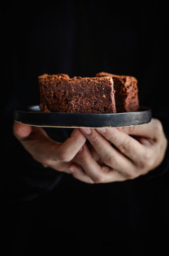 Hands of  woman holding a plate with  brownie