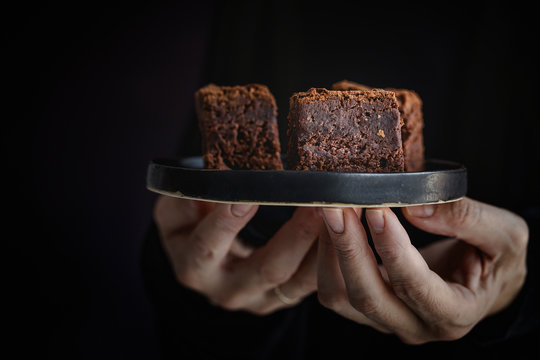 Hands of  woman holding a plate with  brownie