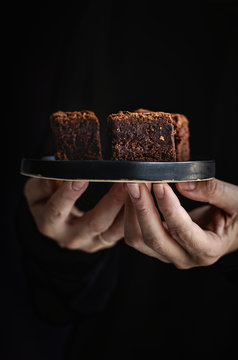 Hands of  woman holding a plate with  brownie