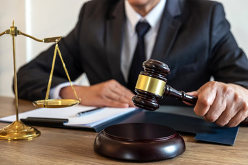 Legal law, advice and justice concept, counselor lawyer or notary working on a documents and report of the important case and wooden gavel, brass scale on table in courtroom