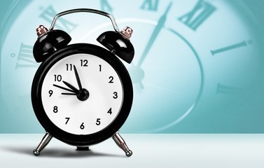 Orange retro alarm clock on wooden table on wall background