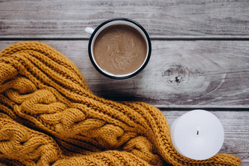 Fototapeta na wymiar Winter cozy concept. Flat lay of orange scarf, candle and coffee with milk drink on wooden table
