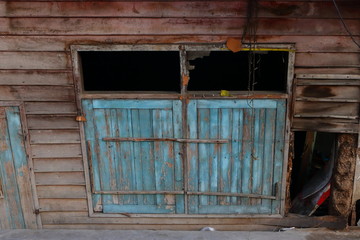 closeup window of leaning abandoned house. the house is below footpath level.
