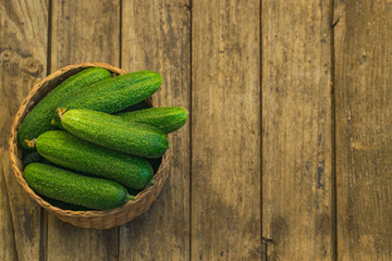 Fresh cucumbers in box on old wooden table