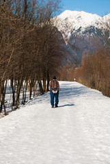 One elderly with wool hat walking on a snowy road