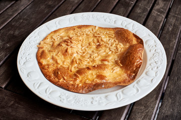 An Olive Oil Torta, a traditional Spanish sweet, on a vintage plate over a rustic wooden table.