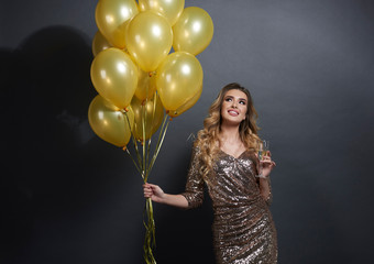 Woman with balloons and champagne looking at copy space