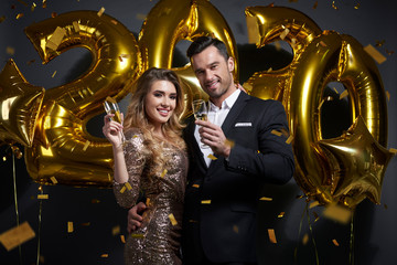 Young couple drinking alcohol under shower of confetti