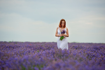 Fototapeta na wymiar Young girl in white dress, posing in a lavender field.