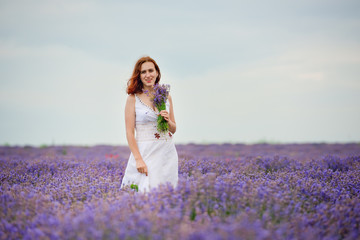 Obraz na płótnie Canvas Young girl in white dress, posing in a lavender field.