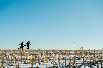 Walk in winter. Young happy people, a guy with a girl, stroll through the snow-covered field. Honeymoon. Love story.