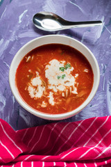 A view of a bowl of tomato soup with sour cream.
