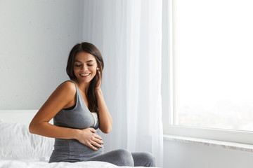 Healthy pregnant woman indoors at home sitting posing.