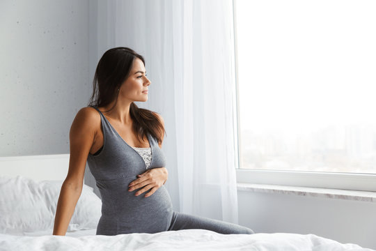 Healthy pregnant woman indoors at home sitting posing.