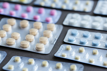 Assorted pharmaceutical packaging of tablets and pills on gray background