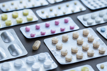 Assorted pharmaceutical packaging of tablets and pills on gray background