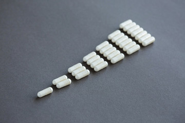 White pills on gray background. Daily medication dosage