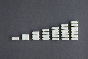 White pills on gray background. Daily medication dosage