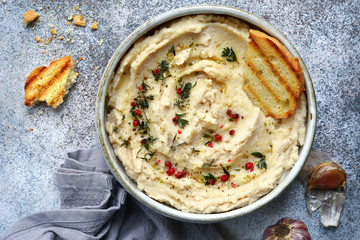 White bean hummus with baked garlic and dried herbs.Top view with copy space.