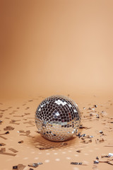 shiny silver disco ball and confetti on beige