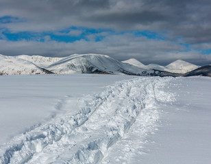 Sledge trace and footprints on winter mountain hill top