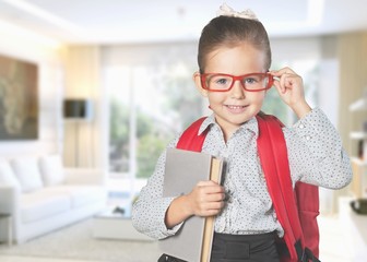 Cute little schoolgirl on blackboard background