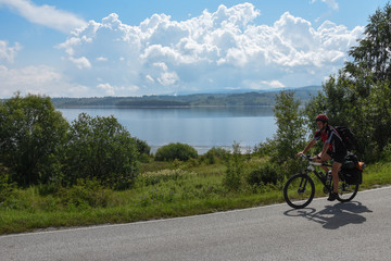 Fototapeta na wymiar Cyclist with a saddle bag near a lake. Traveler on bicycle on sunny day