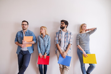 Group of young people standing in line with folders in hands. Serious facial expression, in...