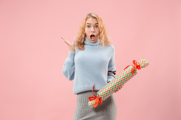 The surprised woman with big colorful gift box. Soft colors. Christmas, birthday, Valentine day, presents. Studio portrait over pink background