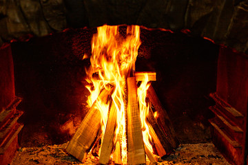 Burning firewood in the fireplace on a dark background.