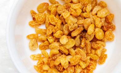 Yellow raisins in a plate as background