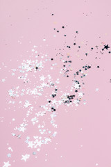 Silver sparkles, stars and glitters on pink background. Festive concept.